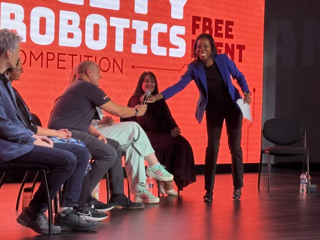 Beverly Clarke MBE hosting a panel discussion at a robotics competition stage.