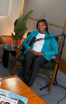 Beverly Clarke MBE sitting in a recording studio with a microphone during a podcast session.