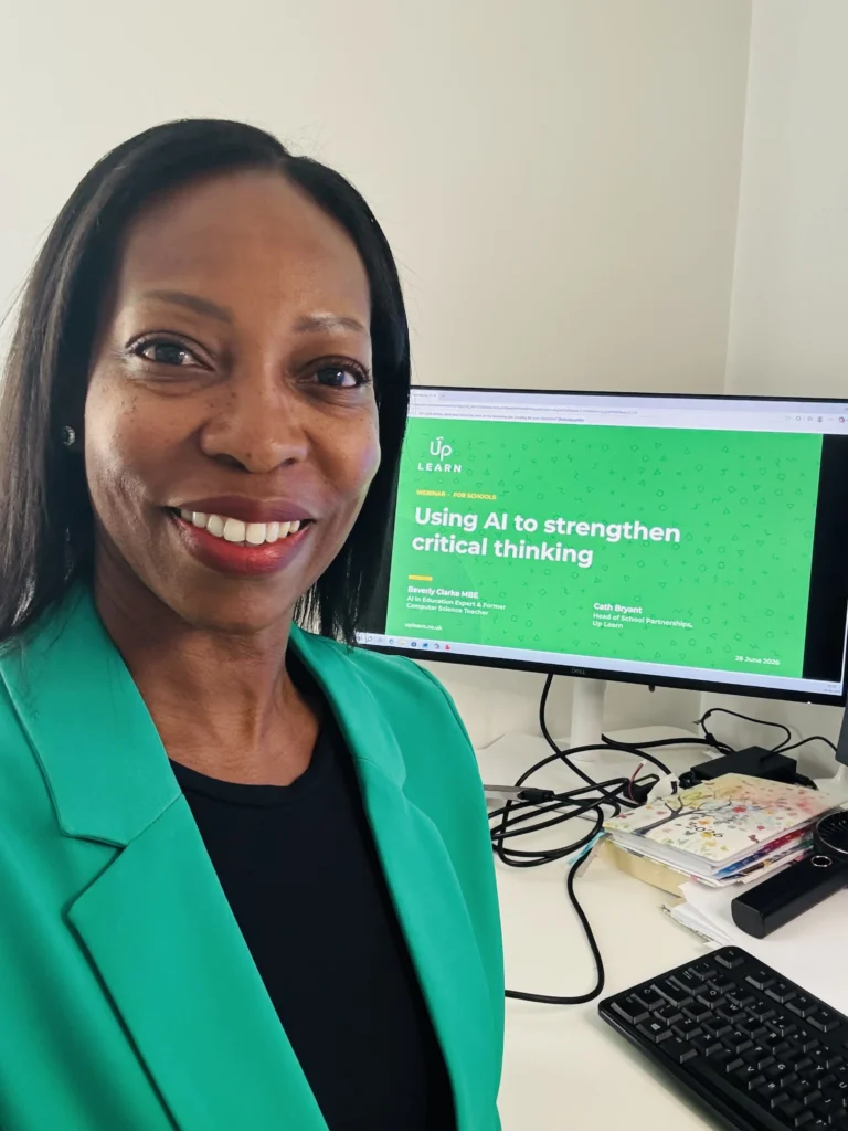 Beverly Clarke MBE smiling in front of a screen displaying an Up Learn webinar on AI and critical thinking.